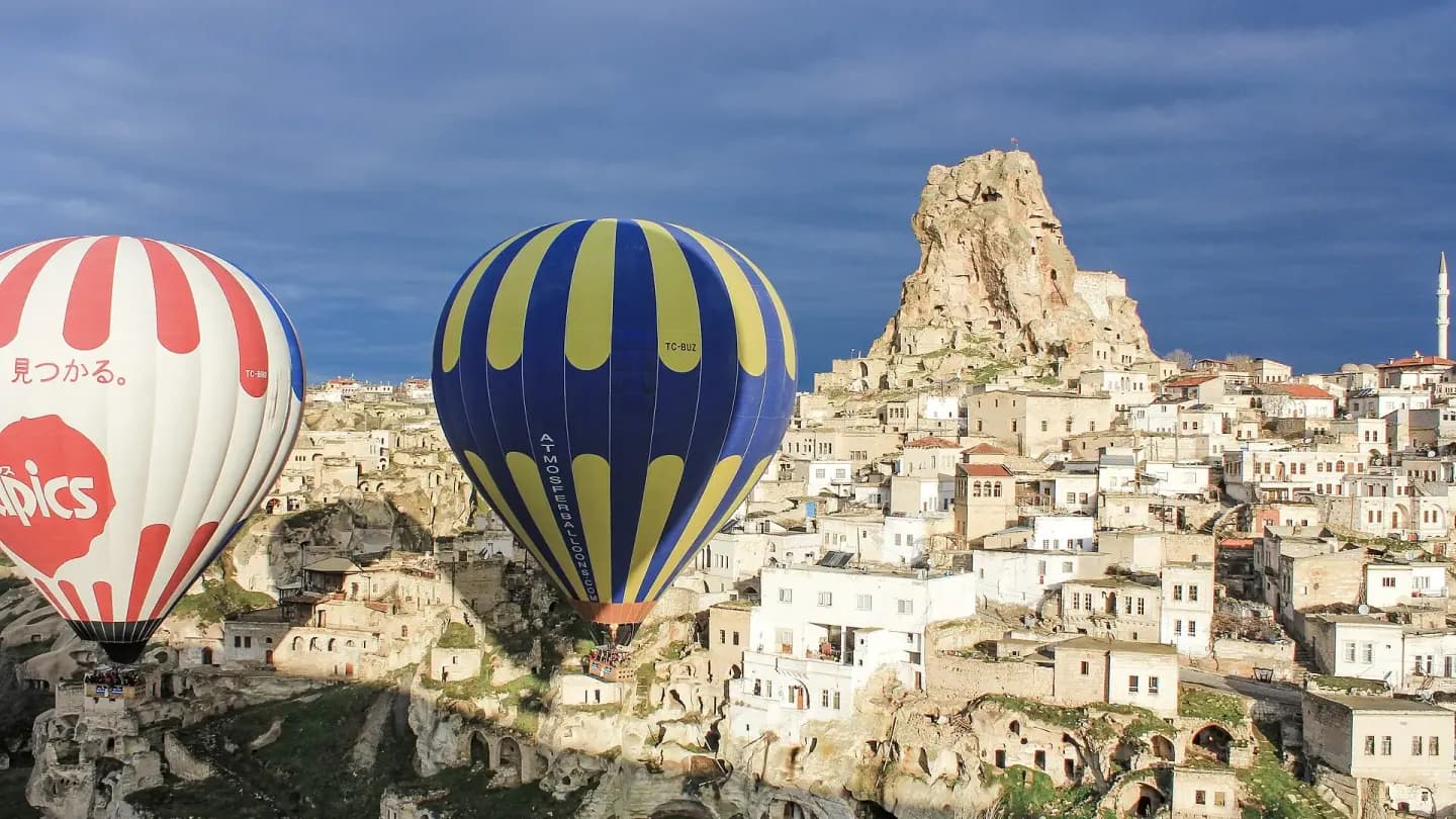 Hot air balloons floating above Cappadocia valley rock formations in Turkey